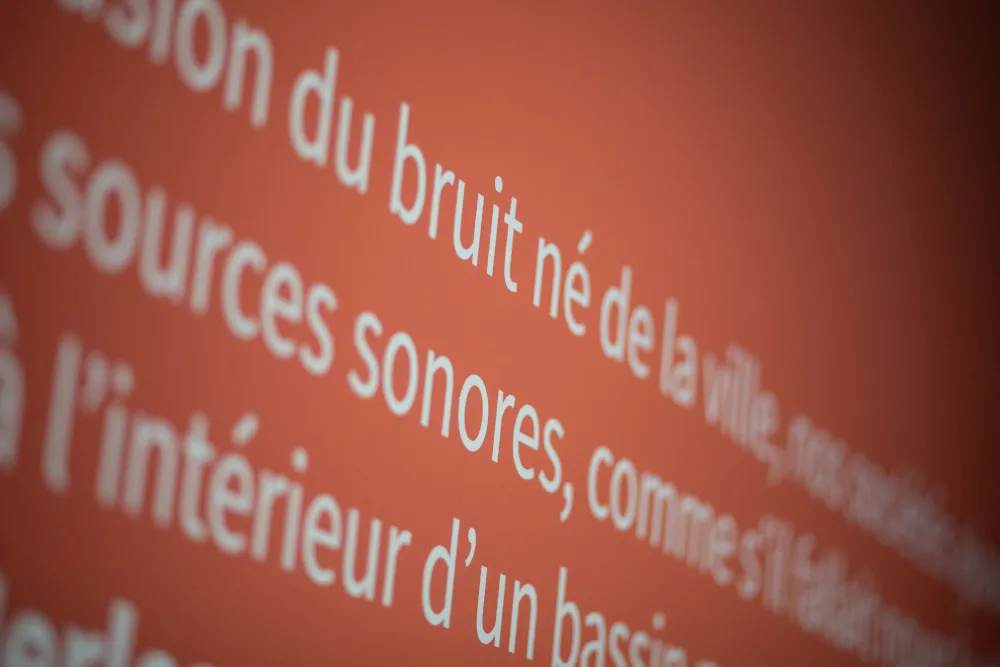 Gros plan sur un texte écrit sur le mur "bruit né de la ville"... "source sonores..."