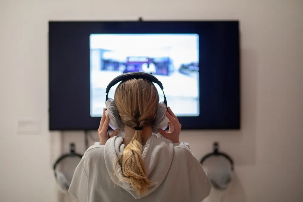 Personne de dos avec un casque auditif devant un téléviseur