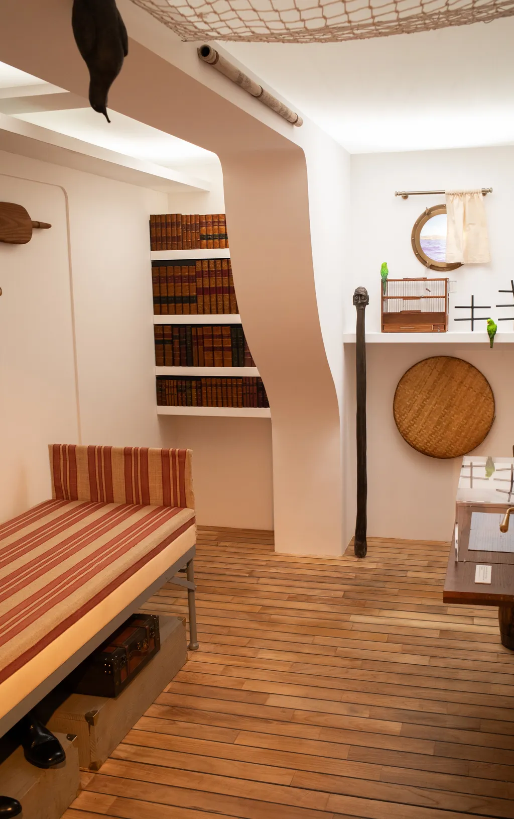 Vue sur une cabine de bateau, un hublot, un lit, une bibliothèque